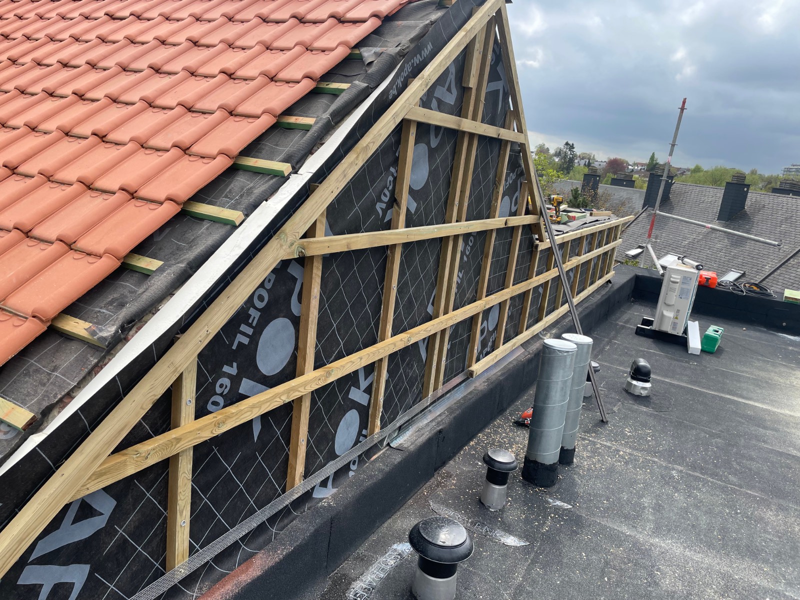 Dakconstructie in opbouw met onderdak en pannen op een hellend dak